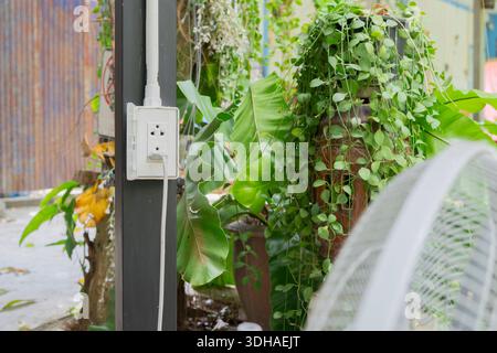 White plug socket setting at outdoor with electric fan power cord on steel pole. Selective focus. Stock Photo