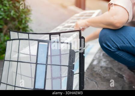 Housekeeper cleaning air conditioning system, washing dirty cover air conditioners on the floor. Selective focus. Maintenance and service concepts Stock Photo