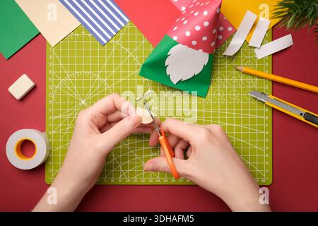 Making a craft. Hands cut out an oval nose from beige paper. Creative process. Stock Photo