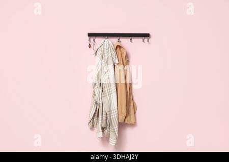 Rack with keys from house and clothes on pink wall Stock Photo
