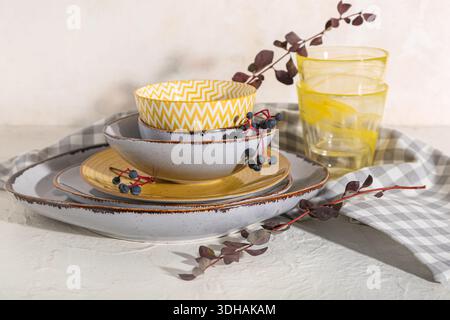 Stack of dishes with autumn branches on table against white background Stock Photo