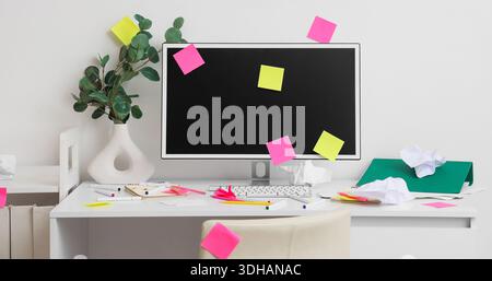 Messy workplace with computer monitor and sticky notes in light office Stock Photo