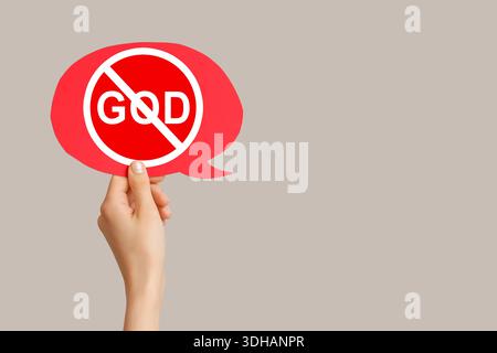 Hand holding speech bubble with crossed-out word GOD on grey background. Atheism concept Stock Photo