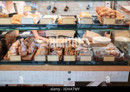 Variety assortment of fresh baked croissants, rolls and sweet pastries displayed in bakery glass showcase Stock Photo