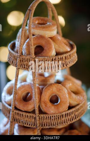 Stacked glazed donuts on wicker basket and blurred golden bokeh showing on stage during wedding celebration Stock Photo
