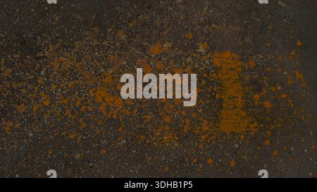 Grungy dark asphalt texture featuring vibrant yellow paint splatters. Weathered industrial urban background is ideal for edgy street-style designs and Stock Photo