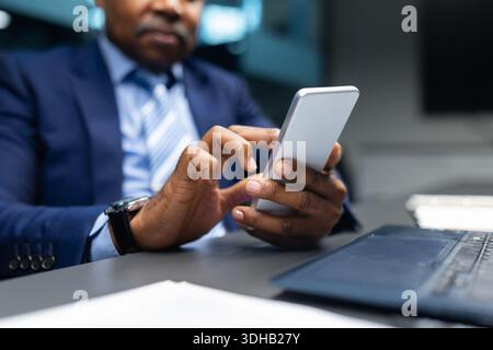 Closeup of African American businessman using smartphone at his desk Stock Photo