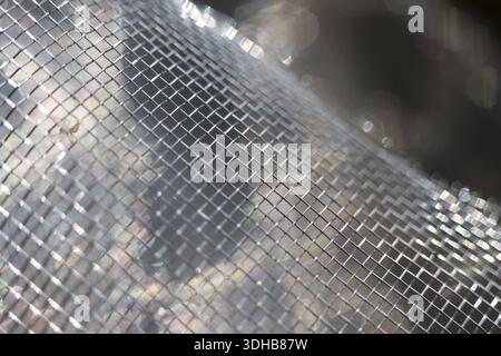 Detailed macro shot featuring silver metallic mesh grid showing shiny texture pattern with industrial surface weave and geometric connection feeling s Stock Photo