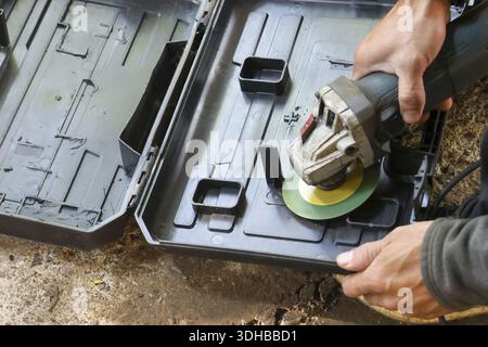 Focused angle grinder worker hand holding power tool inside black storage case ready for construction work with careful industrial preparation Stock Photo