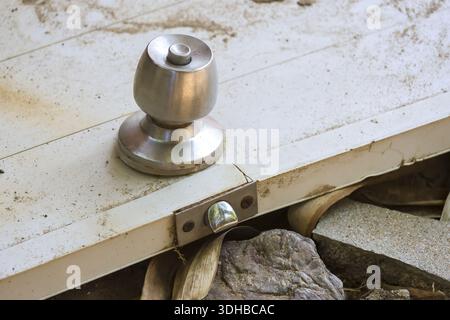Close up view of old silver metal doorknob on broken white wooden door lying on ground abandoned outdoors creating lonely and neglected atmosphere wit Stock Photo