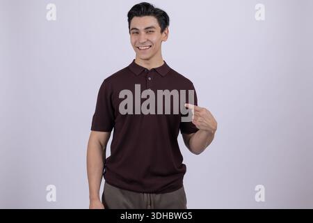 Man in brown shirt pointing himself and looking at camera Stock Photo