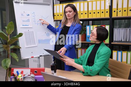 Two professionals engage in a lively discussion about data trends in a modern office setting Stock Photo