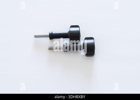 Close-up macro of two thumb screws with a black head positioned horizontally on a clean white background. Ideal for hardware, engineering, product des Stock Photo