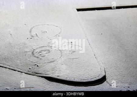 fresh snow on pavement with simple drawn circles, view of a lightly snow covered pavement surface with hand drawn circles visible in the soft snow. th Stock Photo
