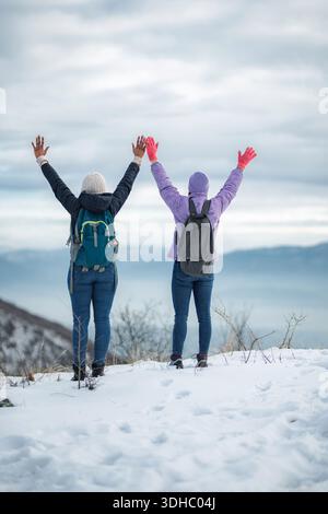 People hiking in snowy mountains celebrating achievement Stock Photo