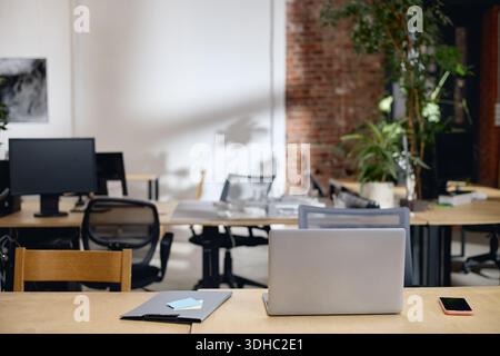 Modern Open Plan Office Workspace Featuring Laptop and Digital Devices Stock Photo
