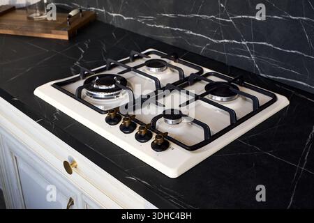 Gas hob cooktop country style design with aesthetic cream colored enamel and antiqued brass control knobs, cast iron grates and gas control function c Stock Photo