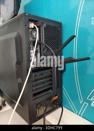 Back view of a desktop computer with cables and antennas against a blue wall Stock Photo