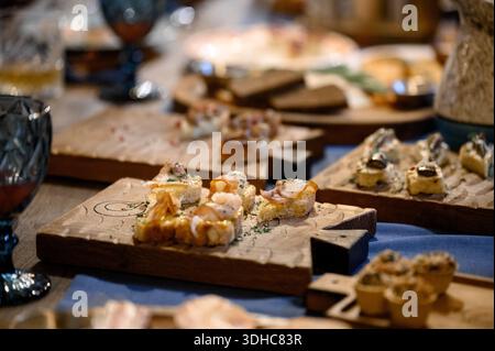 Meat bruschetta on wooden cutting boards on a festive table. Assorted appetizers on baguette with fish and meat served on wood for a banquet reception Stock Photo
