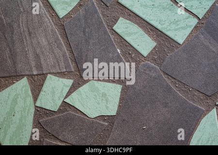 Close-up of irregular light green and gray ceramic tiles arranged on dark grout, forming a textured mosaic surface. Stock Photo