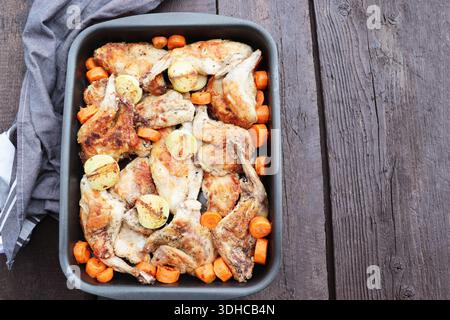 Roasted Rabbit Haunches in Pan with Stewed Vegetables on Rustic Wooden Table Stock Photo