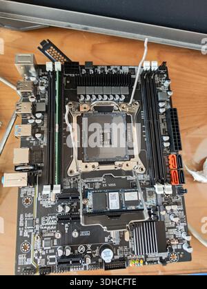 Top-down view of a computer motherboard with CPU socket and components on wooden surface Stock Photo