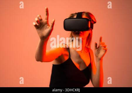 Woman interacting with virtual interface using hand gestures while wearing VR headset, immersive technology and future innovation concept Stock Photo