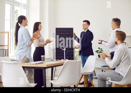 Businessman Presenting Solar Panels To Team Or Clients In Office Meeting Stock Photo