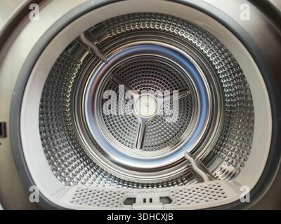 Close-up of a washing machine drum interior, showing metallic perforated surface and central agitator Stock Photo