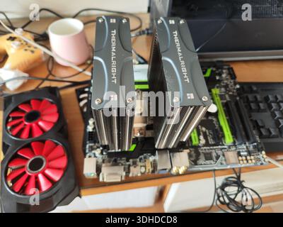 Two Thermalright CPU Coolers Installed on Motherboard with Red Fan in Background Stock Photo
