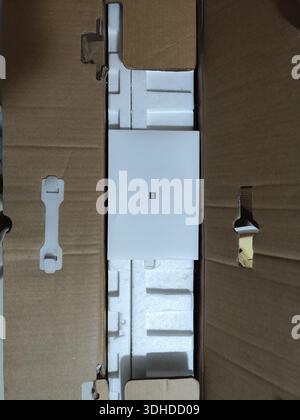 Open cardboard box revealing white electronic device with protective foam packaging Stock Photo