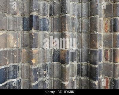 Weathered, vertically structured brick wall made of dark, colored bricks. Part of a historic church portal in the North German Brick Gothic style. Stock Photo