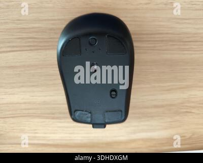 Bottom view of a black computer mouse on a wooden surface Stock Photo