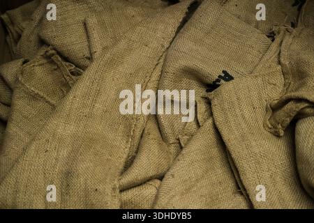 Stacked burlap sacks tied with coarse rope arranged in layers indoors. Stock Photo