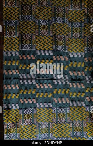 Full frame view of patterned fabric featuring repeating zigzag and diamond motifs in green, mustard and light pink, visible stitching Stock Photo