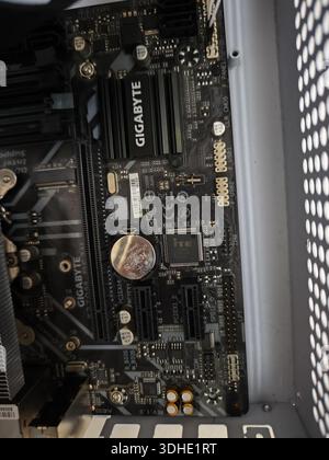 Close-up of Gigabyte motherboard inside computer case with coin for scale Stock Photo