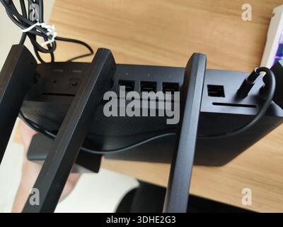 Close-up of a modern router with external antennas and connected cables on a wooden desk Stock Photo