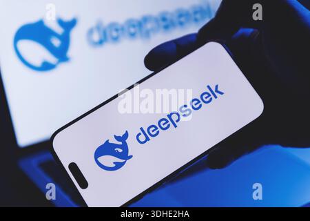 Izmir, Turkey - Jan 21 2026: Hand holding a modern smartphone showing DeepSeek AI app on screen, with a laptop in background also displaying DeepSeek Stock Photo