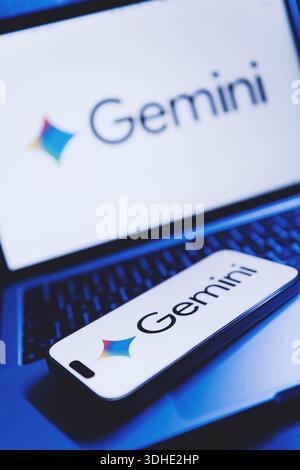 Izmir, Turkey - Jan 21 2026: Photo of a laptop with Gemini AI logo on white background screen, modern smartphone placed on its keyboard also showing G Stock Photo