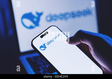 Izmir, Turkey - Jan 21 2026: Hand holding a modern smartphone showing DeepSeek AI app on screen, with a laptop in background also displaying DeepSeek Stock Photo