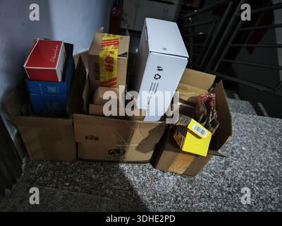 Pile of cardboard boxes and packaging materials stacked on a floor near stairs Stock Photo