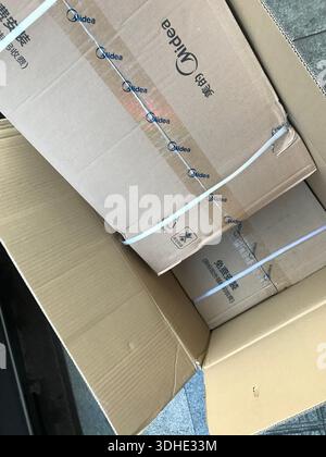 Stacked cardboard boxes with Midea branding, secured with white straps Stock Photo