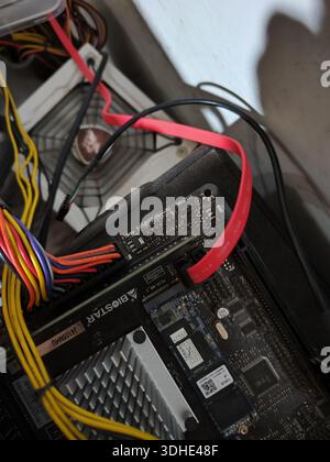 Close-up of computer motherboard with colorful cables and power connectors inside a PC case Stock Photo