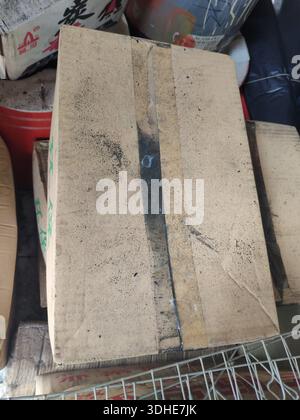 Worn cardboard box with tape and stains, stacked among other items Stock Photo