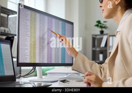 Businesswoman reviewing spreadsheet data on monitor during financial audit in office Stock Photo