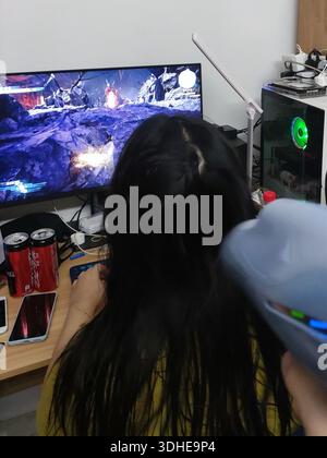 Person Getting Hair Dried While Playing Video Game on Wide Monitor Stock Photo