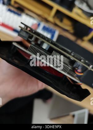 Close-up of a hand holding a graphics card with cooling fan and heatsink Stock Photo