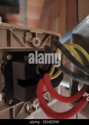 Close-up of electrical wiring and switch socket with red, yellow, and black cables Stock Photo