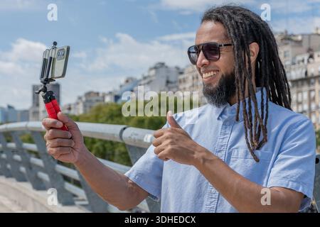 Young Afro-Caribbean man recording a vlog with his smartphone. Stock Photo