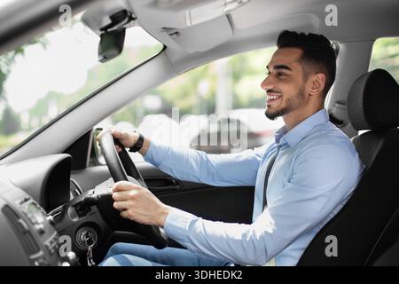 Joyful arabic guy driving nice auto, side view Stock Photo